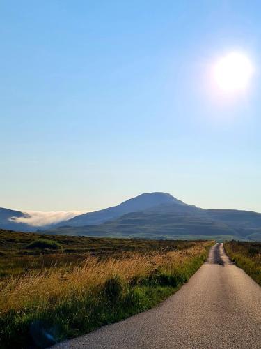 a road in a field with mountains in the distance at Atholl House Skye in Dunvegan