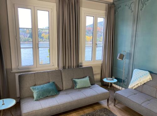a living room with a couch and two windows at RHEIN-SUITES BOPPARD in Boppard