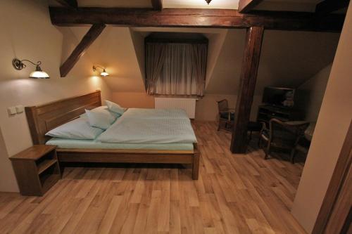 a bedroom with a bed in a room with wooden floors at Hotel Starý Mlýn in Mlýnec