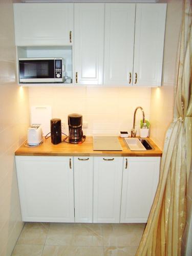 a kitchen with white cabinets and a microwave at Ostsee Hotel-Pension An der Lindenallee in Bad Doberan