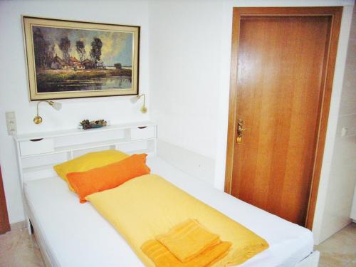 a small bedroom with a white bed with orange and yellow pillows at Ostsee Hotel-Pension An der Lindenallee in Bad Doberan