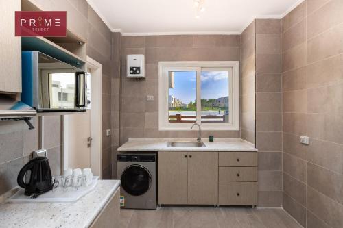 a kitchen with a sink and a washing machine at Prime Select Palm Hills - The Crown in Abū Rawwāsh