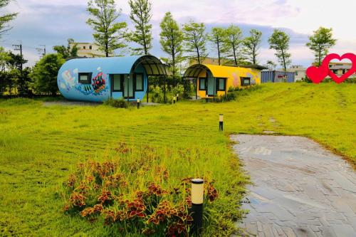 a group of houses in a grassy field with a building at Qian Qian Riverside B&B in Zhuangwei