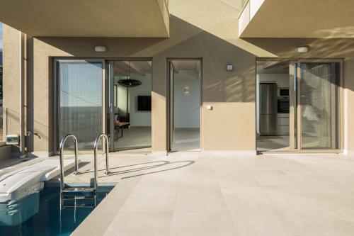 een huis met een zwembad en glazen deuren bij Pearl Villas I, II & III - Redefined island chic, By ThinkVilla in Plakias