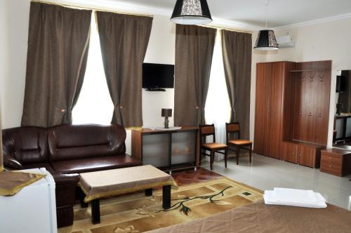 a living room with a leather couch and a table at Hotel Vostok in Sorochinsk