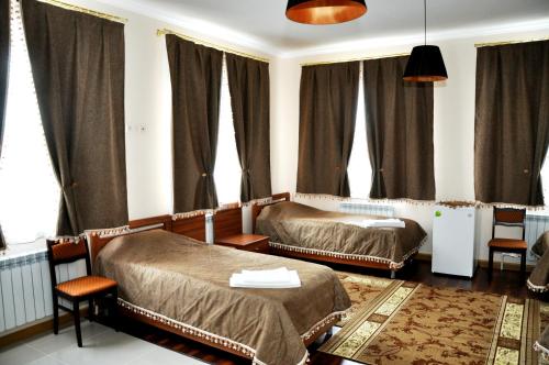 a bedroom with two beds and windows with curtains at Hotel Vostok in Sorochinsk