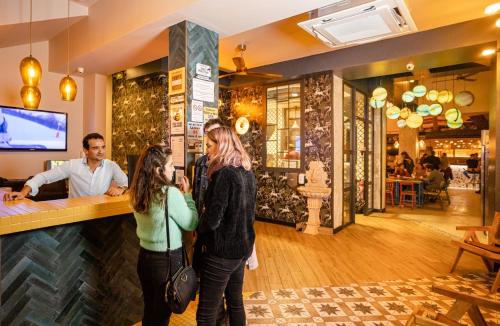 three people standing at a bar in a restaurant at Villa Saint Exupery Beach Hostel in Nice