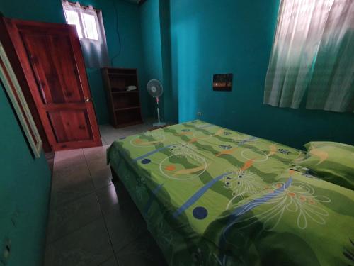 1 dormitorio con 1 cama con edredón verde en Departamento Familiar en Santa Cruz, en Puerto Ayora