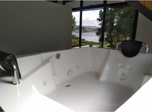 a white bath tub with a window in a bathroom at Coimbra in Chocontá