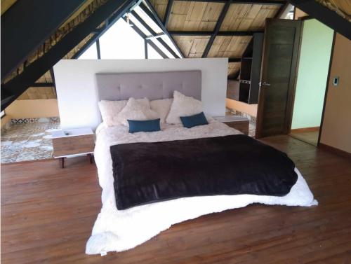 a bedroom with a large bed in a attic at Coimbra in Chocontá