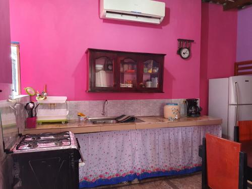 cocina rosa con fregadero y nevera en Departamento Familiar en Santa Cruz, en Puerto Ayora