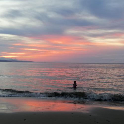a person standing in the water at the beach at Hotel Boutique D Angelo in Manzanillo