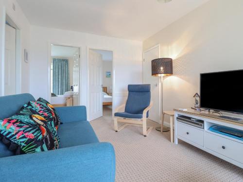 a living room with a blue couch and a television at 48 Glan Y Mor in Fairbourne