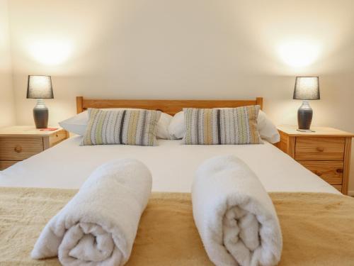 a bedroom with a bed with white towels on it at 48 Glan Y Mor in Fairbourne