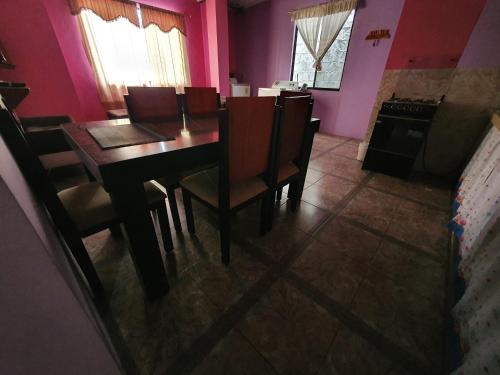 comedor con mesa, sillas y paredes rosas en Departamento Familiar en Santa Cruz, en Puerto Ayora