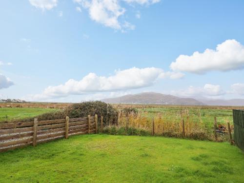 a fence in the middle of a field with a hill in the background at 48 Glan Y Mor in Fairbourne