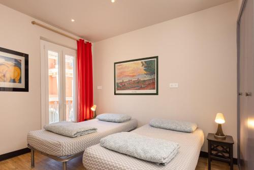 two twin beds in a room with red curtains at Villa Saint Exupery Beach Hostel in Nice