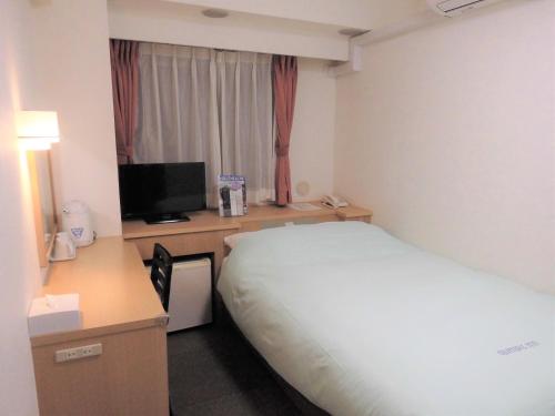 a hotel room with a bed and a desk with a television at Olympic Inn Shibuya in Tokyo