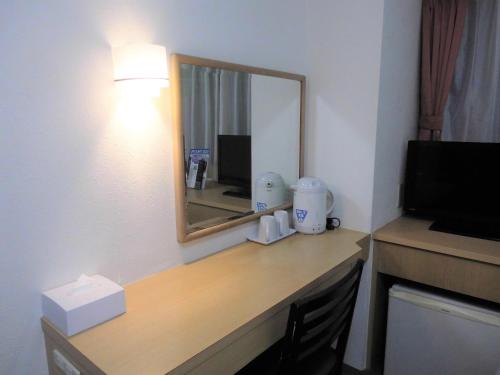 a desk in a hotel room with a mirror at Olympic Inn Shibuya in Tokyo