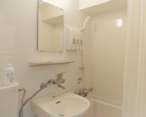 a white bathroom with a sink and a mirror at Olympic Inn Shibuya in Tokyo