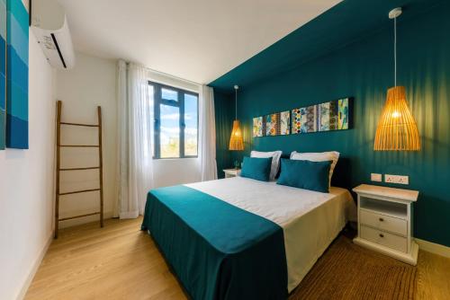 a bedroom with a large bed with blue walls at Les Cerisiers Beach Residence, Cosy and Modern 3 bedroom apartment located 50 metres from the beach and from all amenities and restaurants on the coastal road in Flic-en-Flac
