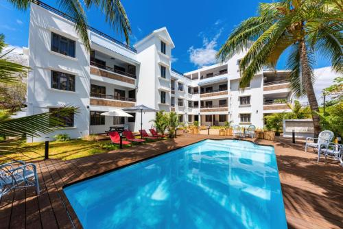 an exterior view of a building with a swimming pool at Les Cerisiers Beach Residence, Cosy and Modern 3 bedroom apartment located 50 metres from the beach and from all amenities and restaurants on the coastal road in Flic-en-Flac