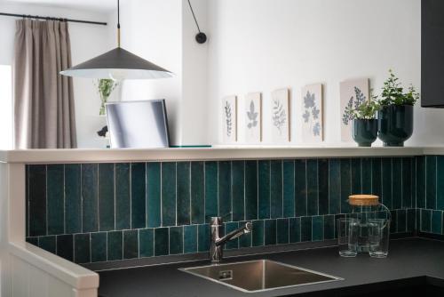 a kitchen with a sink and a green tiled wall at La porticina. Your lake view home. in Barrea
