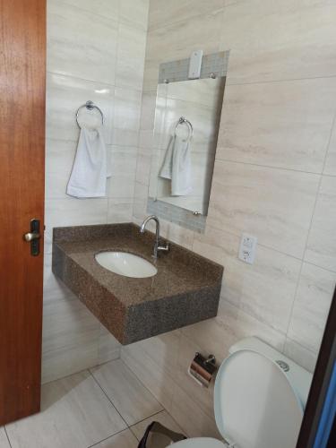 a bathroom with a sink and a toilet and a mirror at D'Casa Hotel e restaurante in Marechal Cândido Rondon