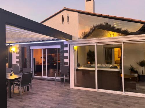 d'une terrasse avec des portes en verre, une table et des chaises. dans l'établissement Mas avec piscine et jacuzzi sur Argeles sur Mer, à Argelès-sur-Mer