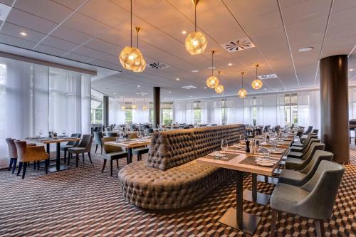 a dining room with tables and chairs and chandeliers at Radisson Blu Hotel Dortmund in Dortmund