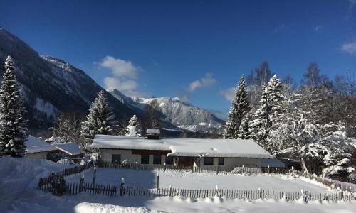 a house covered in snow with mountains in the background at Landhaus Renata Bayrischzell in Bayrischzell