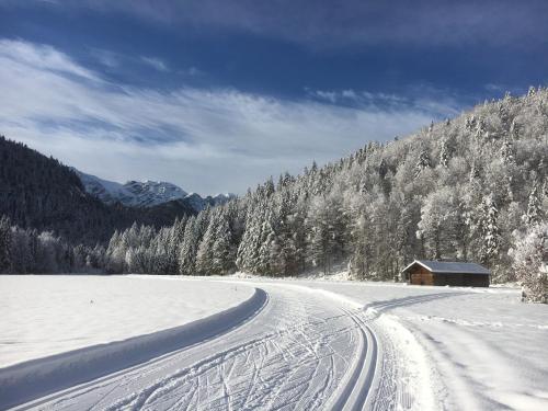 a snow covered road with a house on the side of a mountain at Landhaus Renata Bayrischzell in Bayrischzell