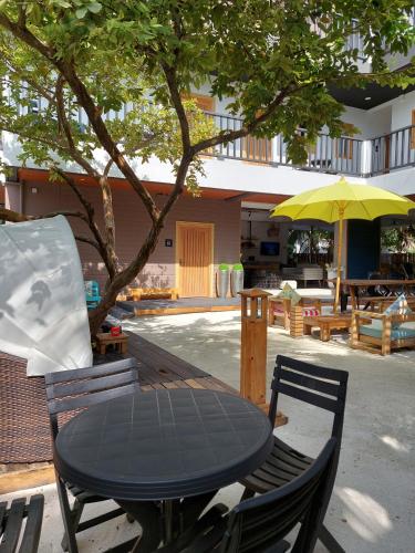 a black table and chairs with a yellow umbrella at Palms Retreat in Fulhadhoo