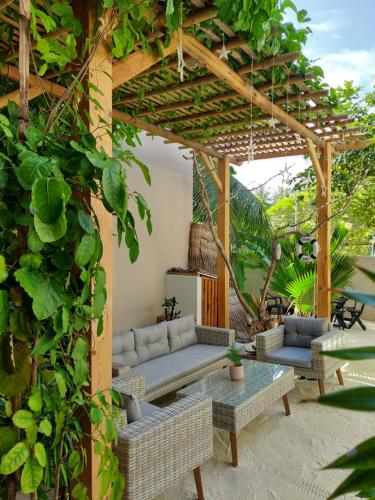 a pergola with a couch and tables in a yard at Palms Retreat in Fulhadhoo