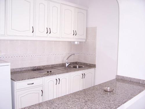 una cocina con armarios blancos y fregadero en La Laguneta en Puerto del Carmen