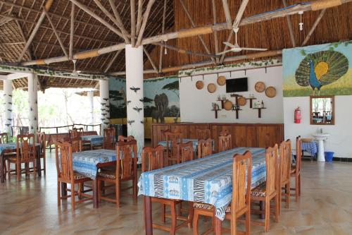 Voyage Village في Mikumi: غرفة طعام مع طاولات وكراسي وتلفزيون