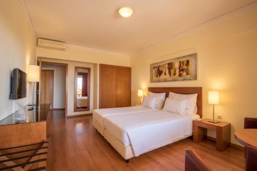 a bedroom with a large white bed and a television at Vila Gale Cerro Alagoa in Albufeira