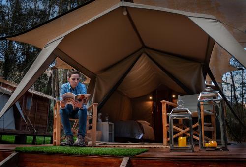 a woman sitting in a tent reading a book at Glamping Chaska Ocupi in Urubamba