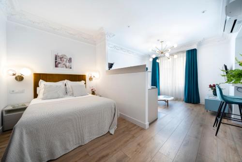 a white bedroom with a large bed and a table at Real Segovia Apartments by Recordis Hotels in Segovia