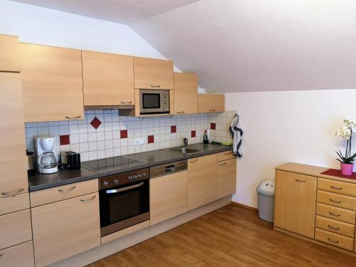 a kitchen with wooden cabinets and a microwave at Maria's Platzl Wagrain in Wagrain