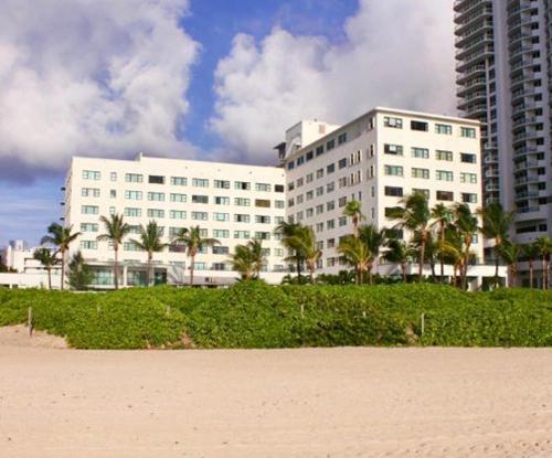 a large white building with palm trees in front of it at CASABLANCA -Kitchen, Pool, Beach- in Miami Beach