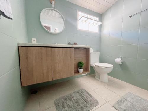 a bathroom with a toilet and a mirror and a sink at La Feliz - Casa de Praia in Porto De Galinhas