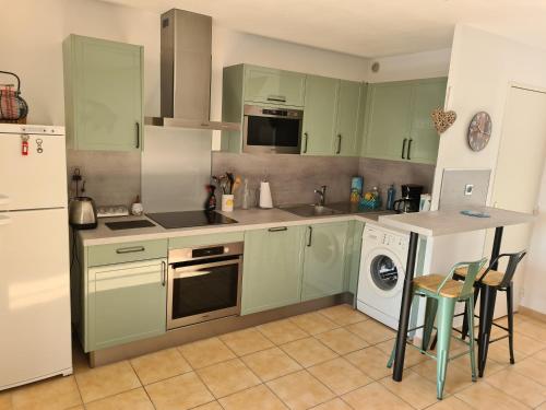 cocina con armarios verdes y encimera en Villa tout confort dans résidence privée avec piscine à 500m de la plage - Climatisation, WIFI, parking, en Portiragnes