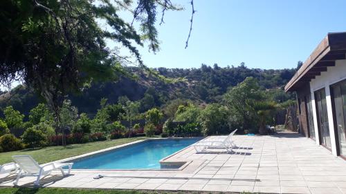 a swimming pool with two chairs and a house at Callihue Lodge in Santa Cruz