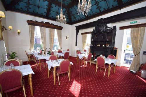 une salle à manger avec des tables, des chaises et des lustres blancs dans l'établissement Three Gables, à Bridlington