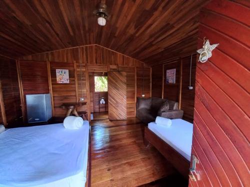 Cabañas Los Laguitos Rio Celeste في El Achiote: غرفة نوم بسريرين واريكة في غرفة