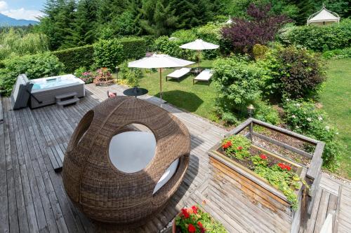 a wooden deck with a wicker chair and a table at Villa Orso Grigio in Ronzone