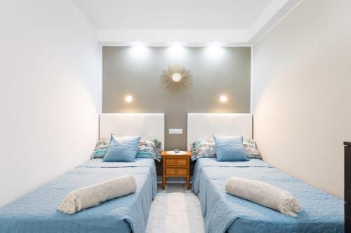 a bedroom with two beds with blue sheets and a table at PARADISE VIEW APARTMENT MASPALOMAS in Maspalomas