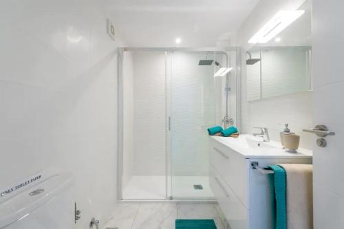 a white bathroom with a shower and a sink at PARADISE VIEW APARTMENT MASPALOMAS in Maspalomas