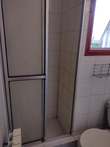 a bathroom with a shower with a toilet and a window at Hostal El Toque de Pilar in Punta Arenas